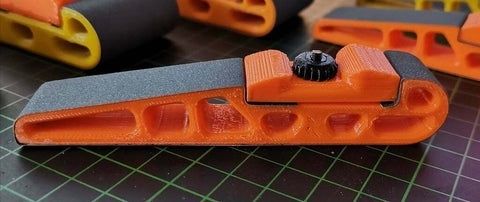 Pièces imprimées en 3D orange et grises sur un tapis de découpe